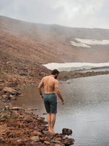 Man standing by a mountain lake...
