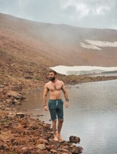 Person standing by a mountain lake.