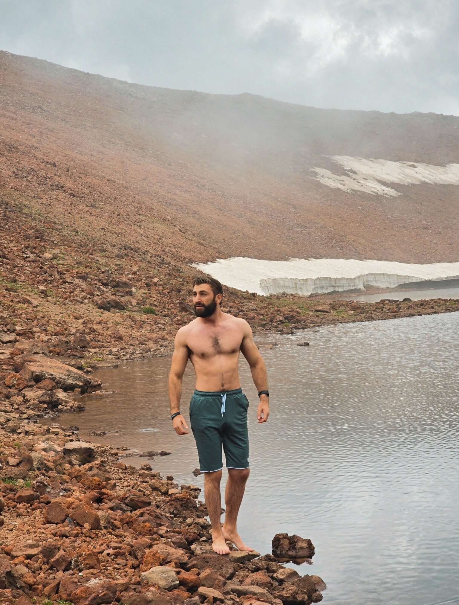 Person standing by a mountain lake.